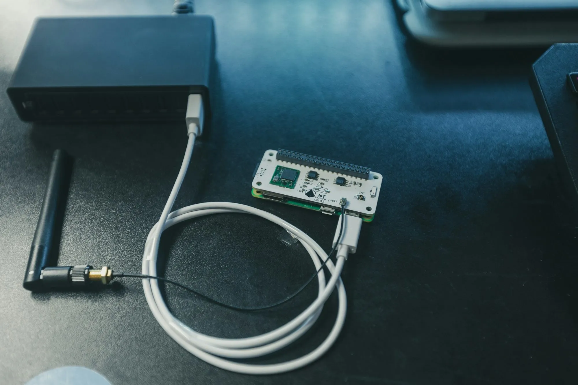 Kleines Funkmodul auf einem Einplatinenrechner, daneben eine Antenne mit Kabel auf dunkler Werkbank